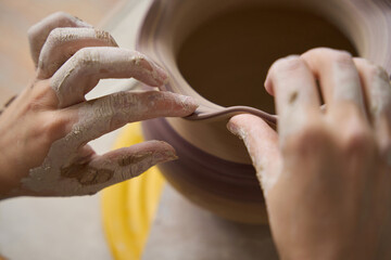 Woman potter leveling the edge of a clay vase
