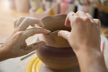Woman potter decorating the rim of a clay vase