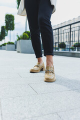 Female legs in black jeans and beige high heels. Beige leather shoes close-up