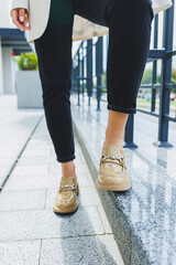 Female legs in black jeans and beige high heels. Beige leather shoes close-up