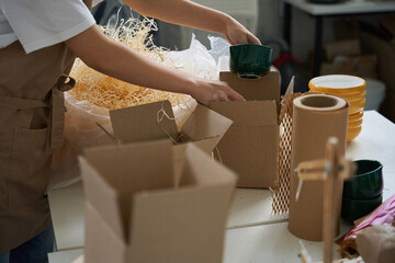 Young woman packing a beautiful cup in a box