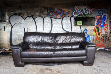 old leather couch in old bunker with graffiti.
