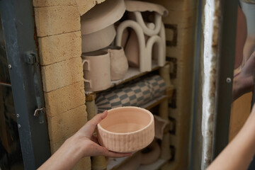 Craftswoman sends a clay vase blank to the pottery kiln