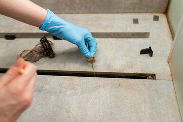 Woman removing hair clump from the shower drain.