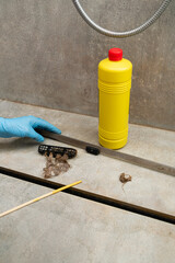 Woman removing hair clump from the shower drain.