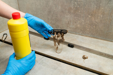 Woman using liquid drain cleaners to clean bathroom sink drain.