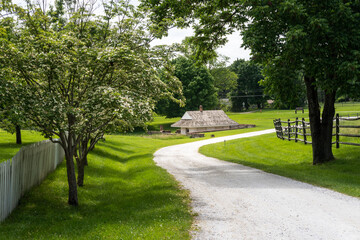 Fototapeta na wymiar The dairy at Hampton National Historic Site in Towson, Maryland. The farm side of the park shows low dairy building built over a spring to keep milk cold. Winding path, flowering trees and fences. 