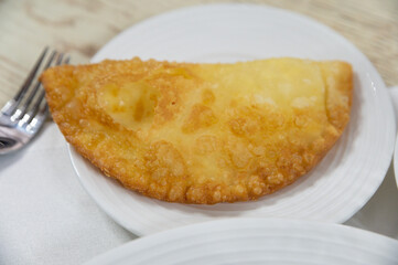 Chebureki or fried pie with meat on plate close up