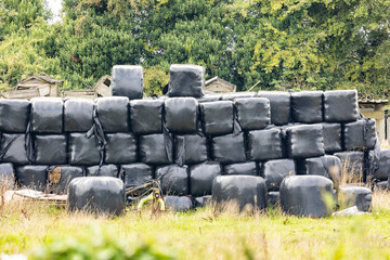 Black plastic covered hay bales, stacked ready for winter use
