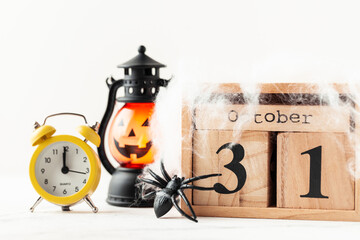 White pumpkin and spooky lantern next to wooden calendar of blocks with the date of October 31...