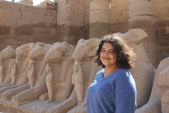 Young teenage girl in the karnak Temple with sphinx statues in the background in Luxor in Egypt