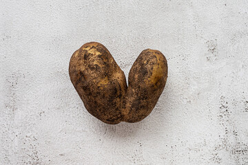 Heart-shaped potato on a gray background. Funny, ugly vegetable or food waste concept