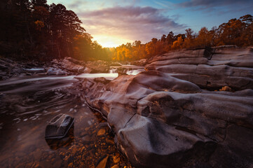 Cossatot Falls State Park at sunset during autumn in Arkansas as the water flows and cascades over smooth boulder rocks with colorful clouds above.   © Thorin Wolfheart