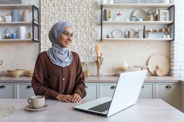 Young beautiful muslim woman in hijab and glasses studying remotely using laptop student woman in...