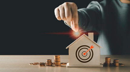 Women hand putting a glowing coin on the model home bank have an icon archery target. with a pile...