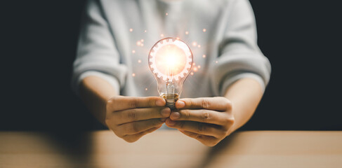 Woman holding a light bulb Inside the lamp, there is a cog logo that is emitting light. are inspiration, ideas, innovation and imagination, business creativity for successful brainstorming, ideas,