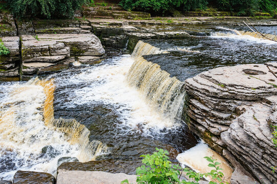 Aysgarth Falls are a three levels one mile stretch waterfalls in Yorkshire Dales National Park, River Ure, Northern England. Long exposure effect photo, selective focus on stones