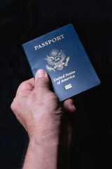 Hand holding USA passport on black background