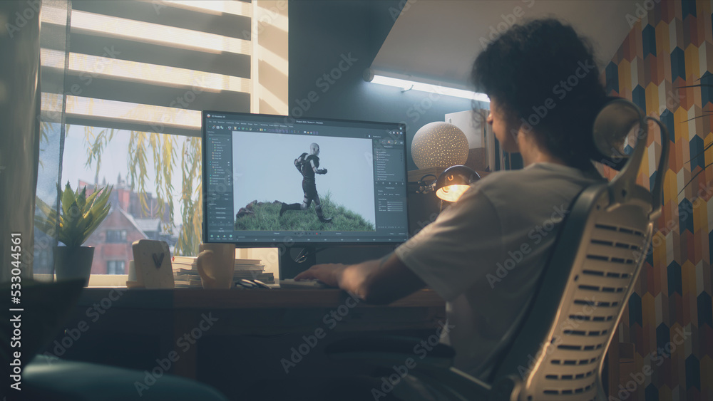 Poster male 3d designer sitting at the table at home and making animation for video game character, using m