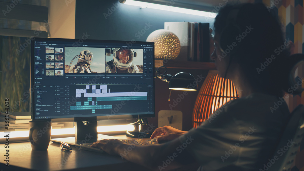 Canvas Prints male editor in headphones sitting at the table at night and editing video with astronauts for custom