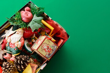 shoebox with decorations and christmas figures messed up on green background. christmas time.
