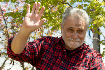 Elderly gentleman is waving with his hand to say hello  © ionkovata