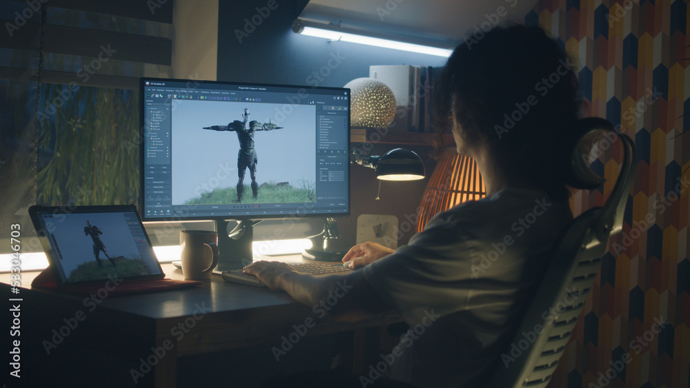 Poster male 3d designer sitting at the table at home and making animation for video game character, using m