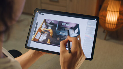 Male 3D designer using digital tablet computer and pencil and creating interior of house in...