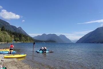 People enjoying beautiful Alouette Lake surrounded by mountains on a sunny summer day in Golden Ears Provincial Park, Maple Ridge.