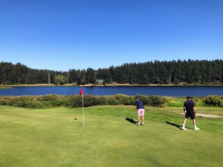 Obraz premium Father and son golfing surrounded by lakes and forest on a beautiful summer day along the sunshine coast, British Columbia, Canada