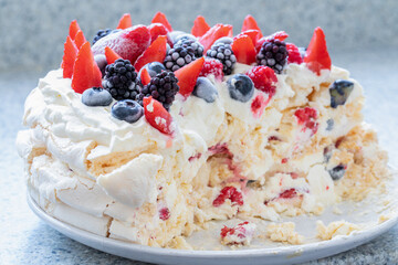 Frozen fruit (strawberries, raspberries, blueberries, blackberries) on a meringue cake and cream. - 533049979