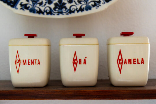 vintage containers for pepper, tea and cinnamon on brown wooden shelf (recipientes para pimenta, ch&aacute; e canela em prateleira de madeira castanha)