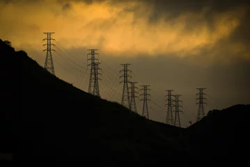  Silhouette of electrical pylons at sunset on the hills above the Zona Norte, or North Zone of Rio de Janeiro, Brazil © Pedro