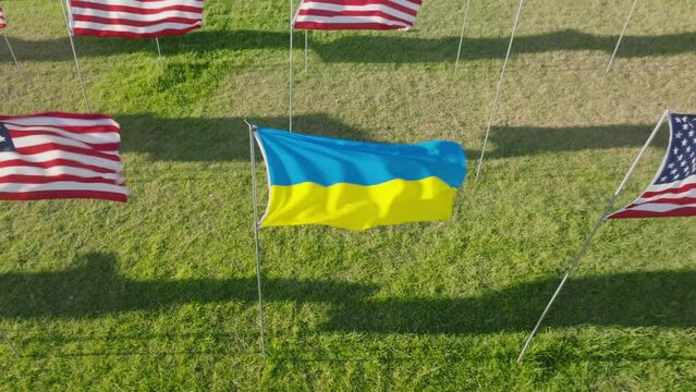 Aerial footage of tribute ceremony with national symbols waving on the wind. Ukrainian and American flags representing multinational victims of terror attack. High quality 4k footage