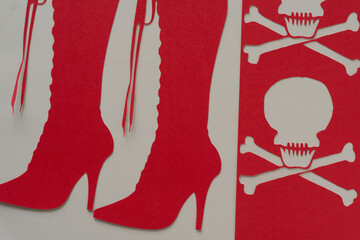red paper stencil with skull heads and glyph or dingbat cutout of tall lace up stiletto boots