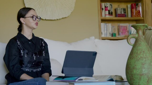 Close-up view of a woman in smart outfit and glasses in antique interior. Caucasian, adult lady in her 30s gives interview with a lavalier microphone on her clothes. Video recording. High quality 4k