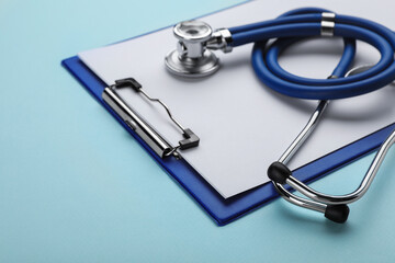 Clipboard with stethoscope on turquoise background, closeup. Space for text
