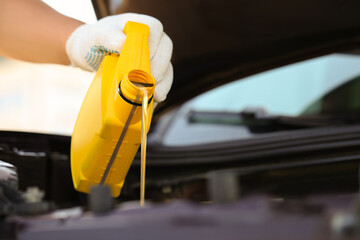 Man pouring motor oil from yellow container, closeup. Space for text