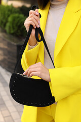 Fashionable woman with stylish bag on city street, closeup