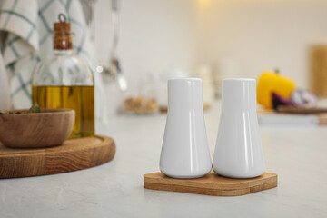 Fototapeta na wymiar Ceramic salt and pepper shakers on white countertop in kitchen, space for text