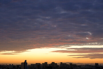 都会の夜明け。神戸市街地からの日の出。オレンジ色に染まる空と雲。神戸市街地から芦屋大阪方面を臨む