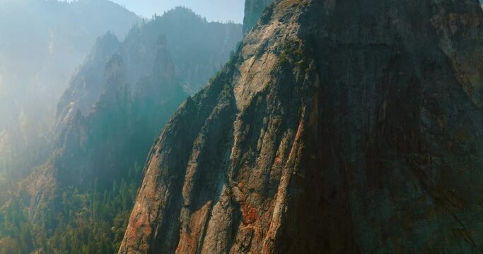 Sharp steep cliffs covered with thick white fog in Yosemite National Park, California, USA. Drone footage among the powerful rocks.