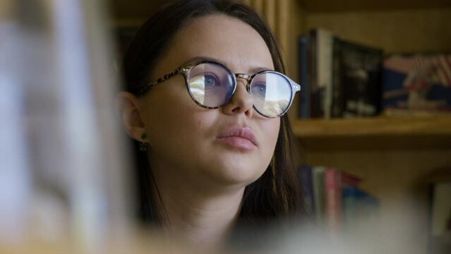 Close-up view of a woman in smart outfit and glasses in antique interior. Caucasian, adult lady in her 30s gives interview with a lavalier microphone on her clothes. Video recording. High quality 4k
