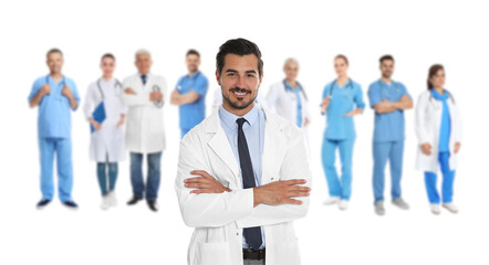 Fototapeta na wymiar Handsome young doctor and blurred view of medical staff on white background. Banner design