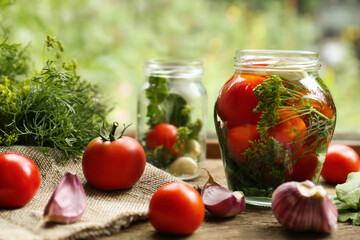 Glass jars, fresh vegetables and herbs on wooden table indoors. Pickling recipe