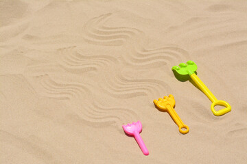 Fototapeta na wymiar Plastic rakes on sand, space for text. Beach toys