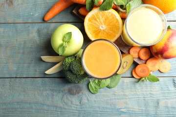 Glasses of delicious juices and fresh ingredients on blue wooden table, flat lay