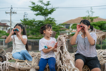 Children kids exploring nature through magnifying glass and binoculars on outdoor playground. The child explores the world through a magnifying glass and binoculars .