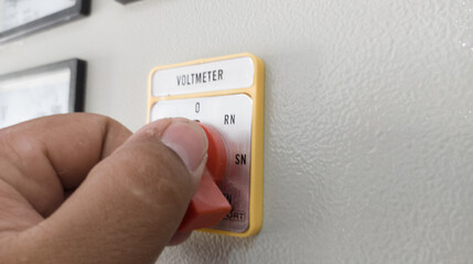 The hand man operating selector switch to control voltage measurement.