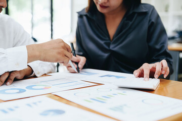 startup business, a portrait of two entrepreneurs using computers, calculators and financial budget documents to plan marketing efforts to increase profits